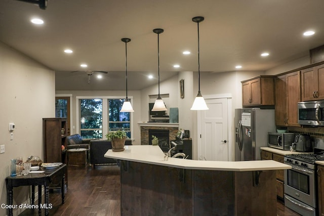 4310 Burns Ct, Sandpoint, ID 83864 - kitchen with stainless steel appliances, light countertops, dark wood-style flooring, a fireplace, and open floor plan