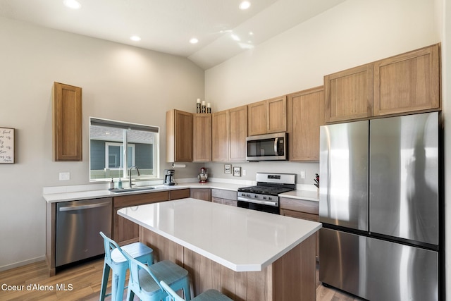 10413 N Belgrave Loop, Hayden, ID 83835 - kitchen featuring appliances with stainless steel finishes, high vaulted ceiling, light wood-style flooring, a kitchen island, and light countertops