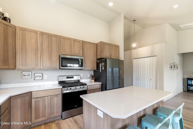 10413 N Belgrave Loop, Hayden, ID 83835 - kitchen featuring appliances with stainless steel finishes, high vaulted ceiling, a breakfast bar, light wood-type flooring, and a kitchen island