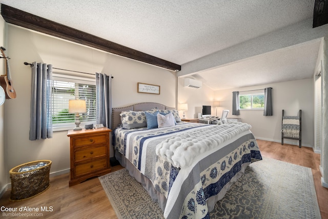 19441 N Rustic Ridge Trl, Rathdrum, ID 83858 - bedroom featuring a wall unit AC, wood finished floors, a textured ceiling, and beamed ceiling
