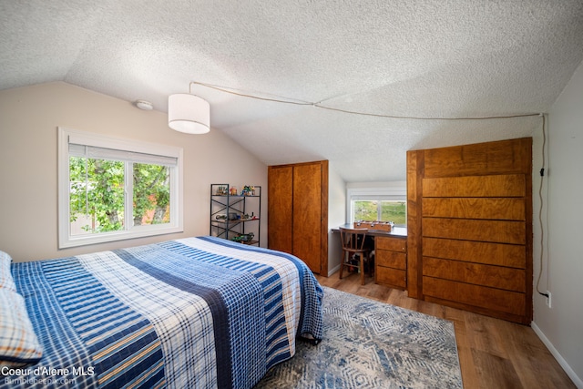 19441 N Rustic Ridge Trl, Rathdrum, ID 83858 - bedroom with lofted ceiling, a textured ceiling, and wood finished floors