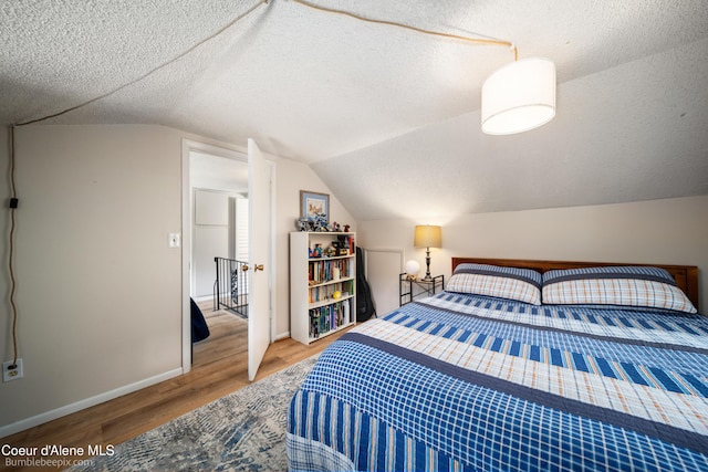 19441 N Rustic Ridge Trl, Rathdrum, ID 83858 - bedroom featuring wood finished floors, vaulted ceiling, and a textured ceiling
