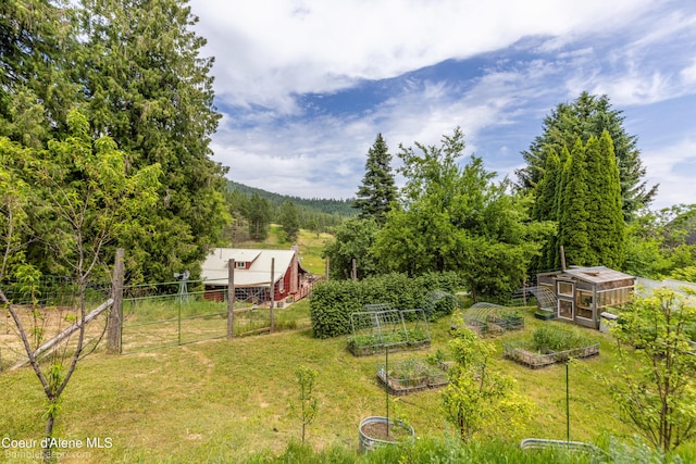 19441 N Rustic Ridge Trl, Rathdrum, ID 83858 - view of yard featuring a vegetable garden, an outbuilding, an exterior structure, and a forest view