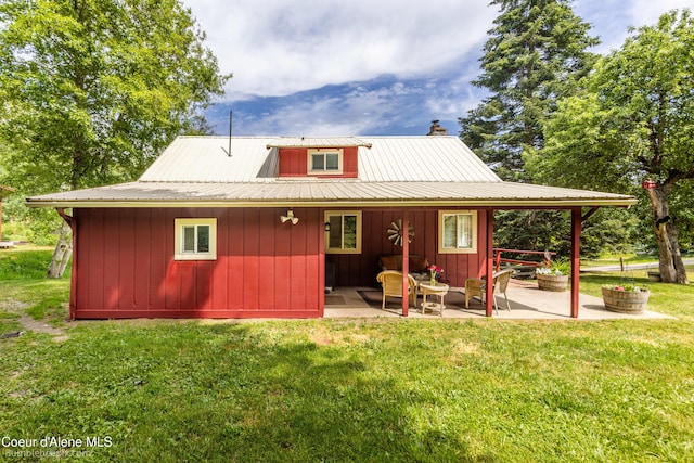 19441 N Rustic Ridge Trl, Rathdrum, ID 83858 - back of property with a patio, a chimney, a yard, a metal roof, and board and batten siding