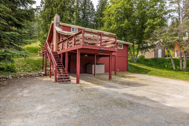 19441 N Rustic Ridge Trl, Rathdrum, ID 83858 - rear view of house featuring dirt driveway, stairs, a deck, and a chimney