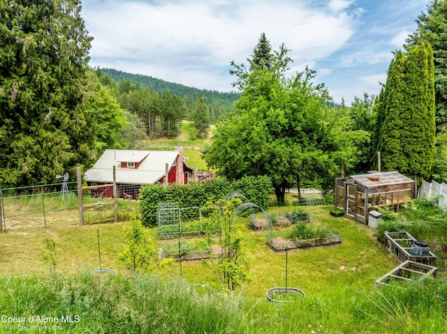 19441 N Rustic Ridge Trl, Rathdrum, ID 83858 - view of yard with a vegetable garden, a view of trees, a greenhouse, and an outbuilding