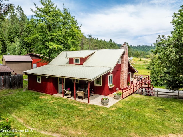 19441 N Rustic Ridge Trl, Rathdrum, ID 83858 - back of house with a patio area, a chimney, a metal roof, and a wooded view