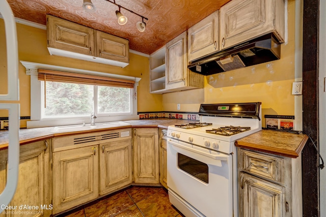 421 W Walnut Ave, Coeur Dalene, ID 83814 - kitchen with white range with gas stovetop, under cabinet range hood, light countertops, dark tile patterned floors, and crown molding