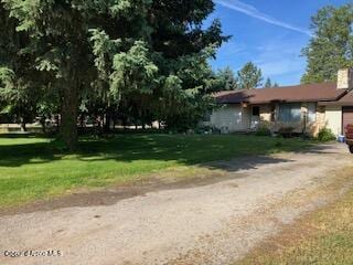 1475 N Maverick Ln, Post Falls, ID 83854 - view of front facade featuring an attached garage, a front yard, a chimney, and driveway