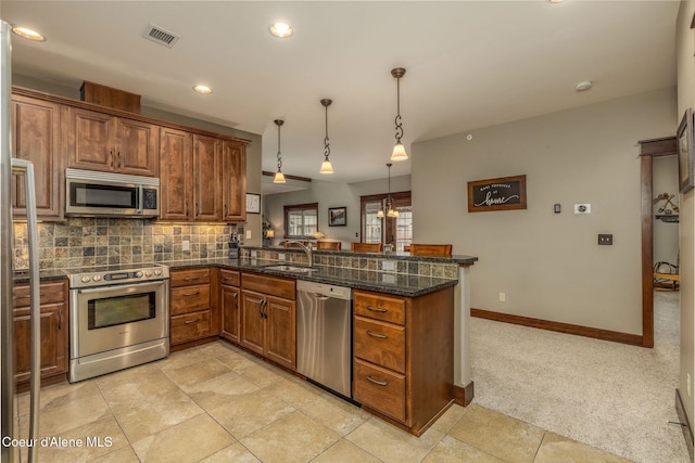 2050 N Main St, Coeur Dalene, ID 83814 - kitchen featuring stainless steel appliances, a peninsula, brown cabinetry, backsplash, and decorative light fixtures
