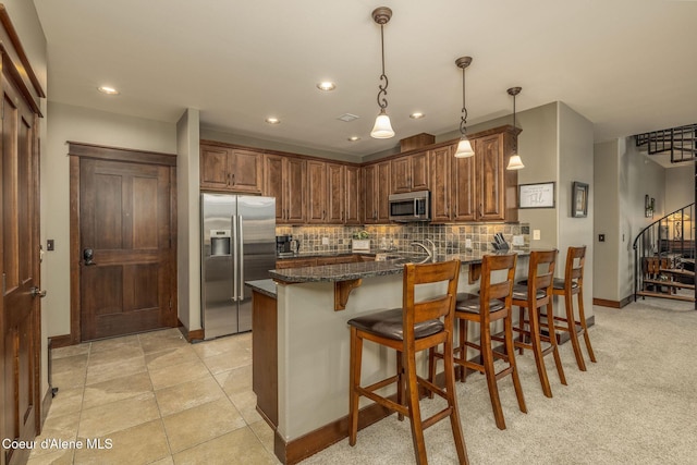 2050 N Main St, Coeur Dalene, ID 83814 - kitchen featuring stainless steel appliances, a peninsula, dark stone countertops, backsplash, and a breakfast bar