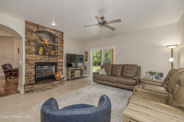 12608 N Shamrock St, Hayden, ID 83835 - living area with arched walkways, a ceiling fan, a large fireplace, and a textured ceiling