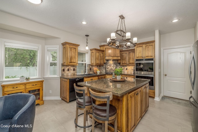 12608 N Shamrock St, Hayden, ID 83835 - kitchen featuring appliances with stainless steel finishes, brown cabinets, decorative backsplash, a kitchen island, and a chandelier