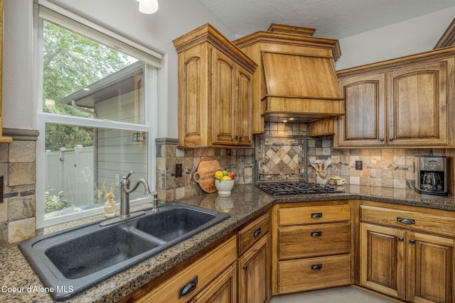 12608 N Shamrock St, Hayden, ID 83835 - kitchen featuring gas cooktop, custom range hood, tasteful backsplash, brown cabinetry, and dark stone countertops