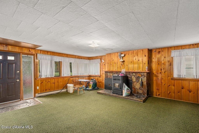1875 S Gateway Ranch Rd, Coeur Dalene, ID 83814 - unfurnished room featuring carpet floors, wood walls, a baseboard radiator, and a wood stove