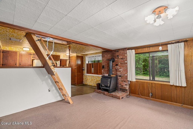 1875 S Gateway Ranch Rd, Coeur Dalene, ID 83814 - unfurnished living room with a wood stove, carpet flooring, and wood walls