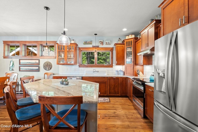 4127 Sagle Rd, Sagle, ID 83860 - kitchen featuring appliances with stainless steel finishes, brown cabinets, tasteful backsplash, under cabinet range hood, and recessed lighting