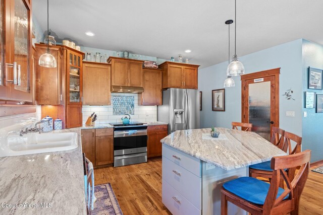 4127 Sagle Rd, Sagle, ID 83860 - kitchen with stainless steel appliances, brown cabinets, a kitchen bar, a center island, and light wood-style floors