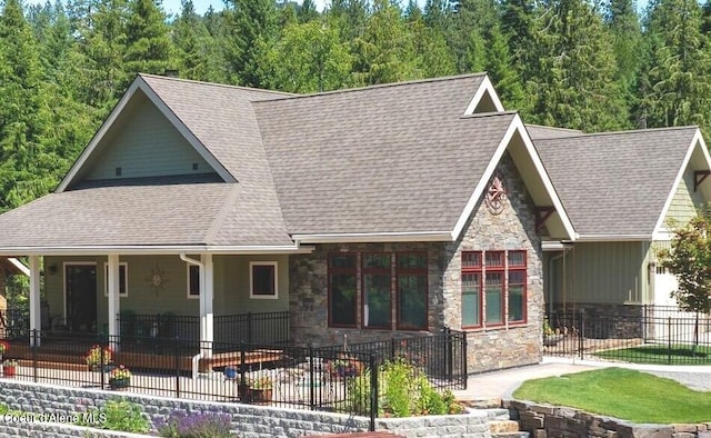 4127 Sagle Rd, Sagle, ID 83860 - view of front of house with stone siding, a patio area, roof with shingles, and a view of trees