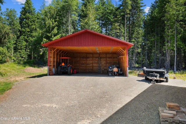 4127 Sagle Rd, Sagle, ID 83860 - garage with a carport, driveway, and a view of trees