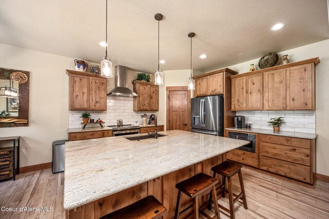 21315 N Eclipse Rd, Rathdrum, ID 83858 - kitchen with appliances with stainless steel finishes, wall chimney range hood, light wood-style floors, tasteful backsplash, and a breakfast bar area