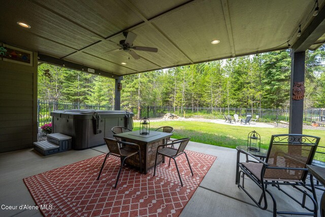 21315 N Eclipse Rd, Rathdrum, ID 83858 - fenced backyard featuring a hot tub, outdoor dining area, ceiling fan, a patio area, and a view of trees