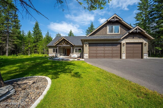 21315 N Eclipse Rd, Rathdrum, ID 83858 - craftsman house featuring stone siding, driveway, a front lawn, a garage, and roof with shingles