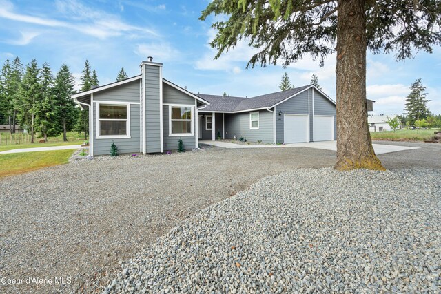 185 Leo Ln, Moyie Springs, ID 83845 - view of front of home featuring concrete driveway, an attached garage, and a chimney