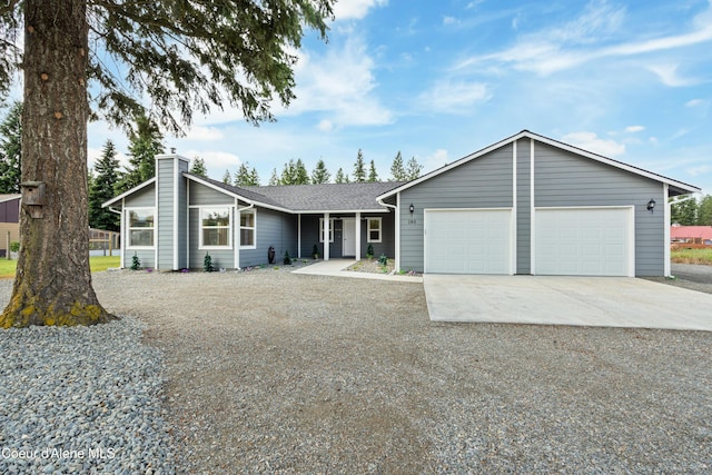 185 Leo Ln, Moyie Springs, ID 83845 - view of front facade with concrete driveway, an attached garage, a chimney, and a shingled roof