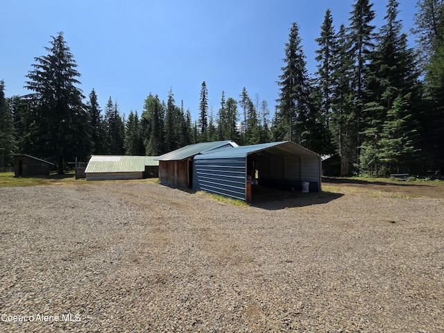 475 Old Range Rd, Clark Fork, ID 83811 - view of outbuilding featuring a detached carport, driveway, and a view of trees