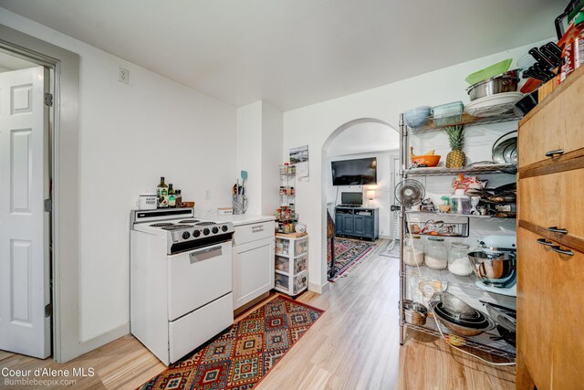 219 E 4th St, Oldtown, ID 83822 - kitchen with white range with electric cooktop, light wood finished floors, arched walkways, light countertops, and white cabinetry