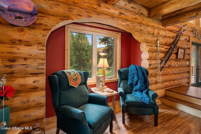 26443 S Farup Rd, Worley, ID 83876 - living area featuring log walls, wood finished floors, arched walkways, and beam ceiling