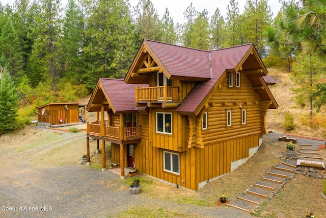 26443 S Farup Rd, Worley, ID 83876 - view of front of house featuring board and batten siding, log siding, a balcony, and an outdoor structure