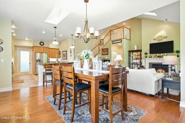 30 Beacon Hill Rd, Cocolalla, ID 83813 - dining room featuring a skylight, light wood-style floors, a warm lit fireplace, a chandelier, and a high ceiling