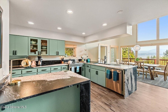 6101 Bottle Bay Rd, Sagle, ID 83860 - kitchen with green cabinets, stainless steel appliances, a peninsula, a mountain view, and light wood-style flooring