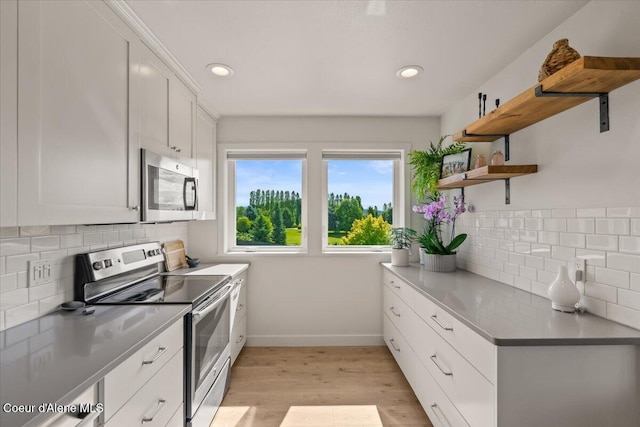6744 E Greta Ave, Post Falls, ID 83854 - kitchen with appliances with stainless steel finishes, open shelves, light wood-style floors, decorative backsplash, and white cabinets