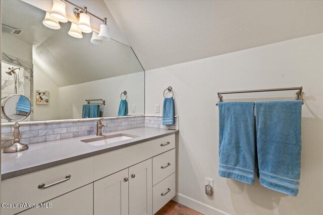 6744 E Greta Ave, Post Falls, ID 83854 - bathroom featuring lofted ceiling, tasteful backsplash, vanity, and wood finished floors