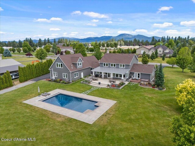 6744 E Greta Ave, Post Falls, ID 83854 - rear view of property featuring a yard, a patio, an outdoor pool, a mountain view, and a residential view