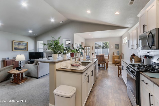 4574 N Connery Loop, Post Falls, ID 83854 - kitchen with appliances with stainless steel finishes, lofted ceiling, open floor plan, white cabinets, and an island with sink