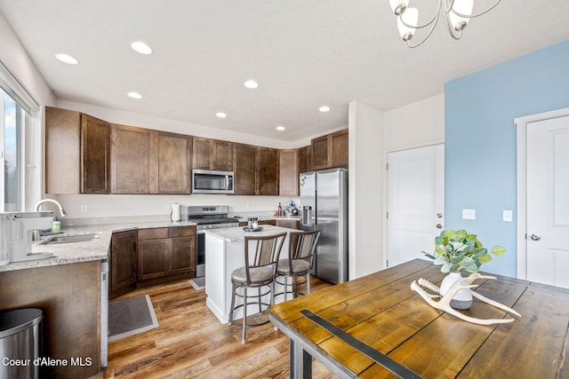 3664 W Belgrave Way, Hayden, ID 83835 - kitchen featuring stainless steel appliances, light wood-style flooring, recessed lighting, a center island, and light stone countertops