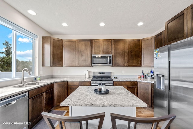 3664 W Belgrave Way, Hayden, ID 83835 - kitchen with appliances with stainless steel finishes, recessed lighting, light stone counters, dark brown cabinetry, and a textured ceiling