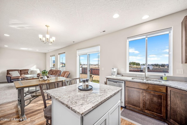 3664 W Belgrave Way, Hayden, ID 83835 - kitchen with stainless steel dishwasher, light wood-style flooring, open floor plan, recessed lighting, and a chandelier