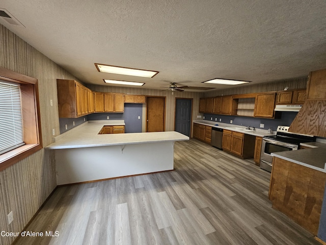 503 E Railroad Ave, Post Falls, ID 83854 - kitchen with stainless steel appliances, under cabinet range hood, a peninsula, wood finished floors, and a textured ceiling