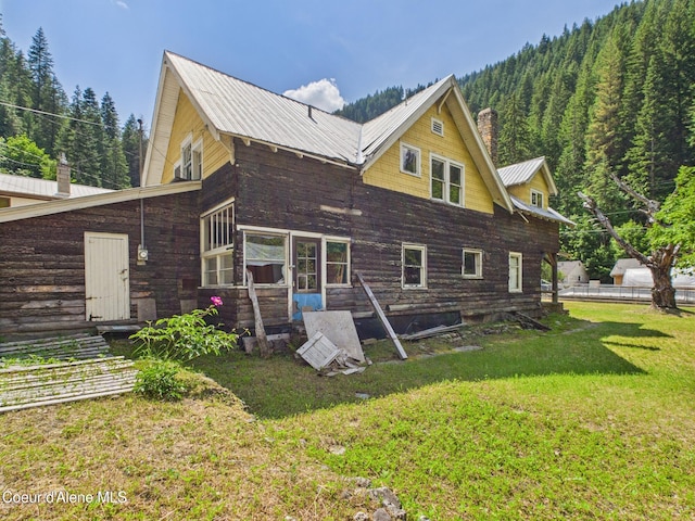 185 King St, Wallace, ID 83873 - back of property featuring a chimney, a yard, a metal roof, and a wooded view
