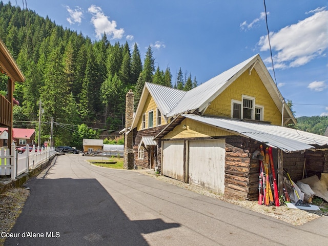 185 King St, Wallace, ID 83873 - view of property exterior featuring a metal roof, a garage, and a chimney