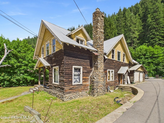 185 King St, Wallace, ID 83873 - view of home's exterior featuring a chimney, a garage, a yard, a metal roof, and stone siding