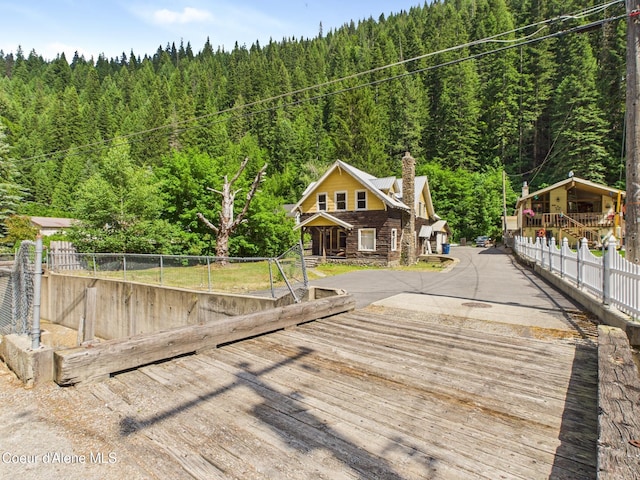 185 King St, Wallace, ID 83873 - view of front of house featuring a forest view, a chimney, a wooden deck, and stone siding