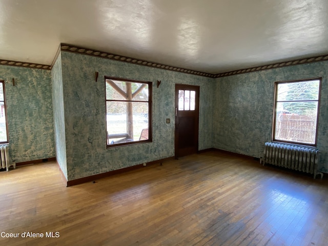 185 King St, Wallace, ID 83873 - entryway with radiator heating unit, wallpapered walls, hardwood / wood-style floors, and crown molding