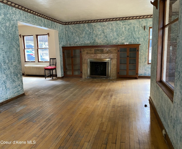 185 King St, Wallace, ID 83873 - unfurnished living room with wallpapered walls, radiator heating unit, hardwood / wood-style floors, plenty of natural light, and a fireplace