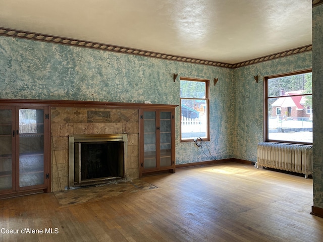 185 King St, Wallace, ID 83873 - unfurnished living room featuring radiator heating unit, wood-type flooring, wallpapered walls, and a fireplace
